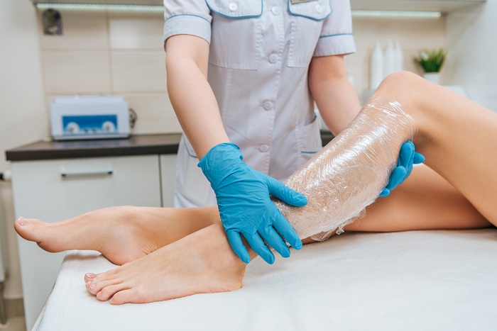 Cosmetologists using body plastic wraps to treat patients