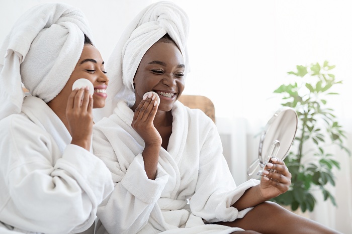 Female friends in bath robes cleansing faces