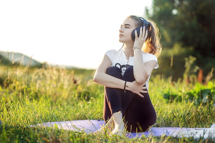 Woman doing yoga and music theraphy outdoors