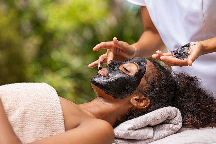 Woman getting charcoal facial treatment