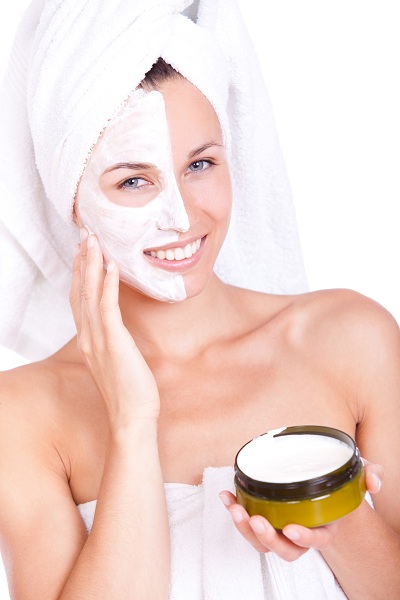 Woman in bath towel with face mask cream on