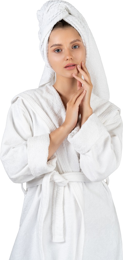 Woman in her bathrobe towel moisturizing her face