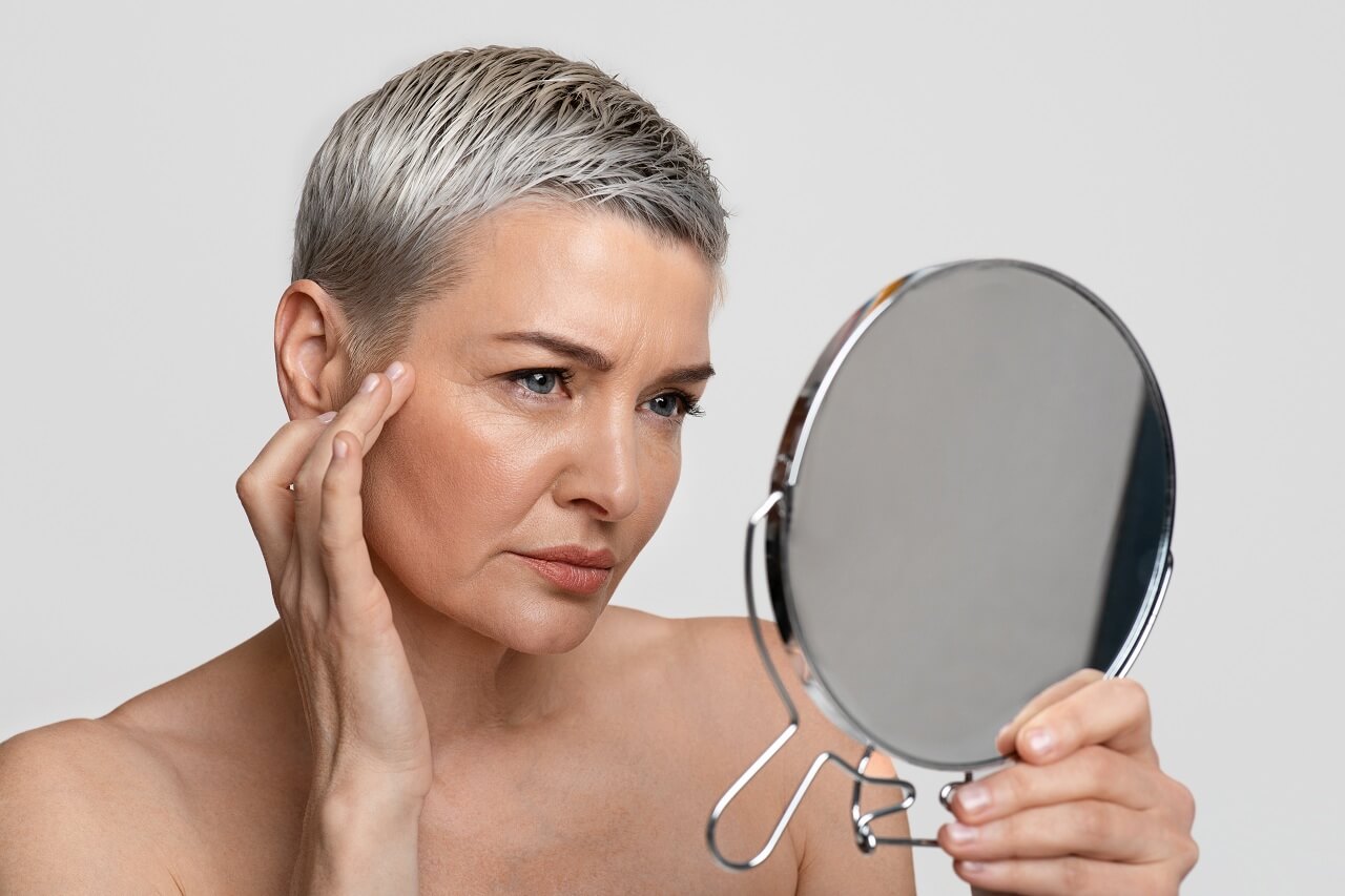 aging woman looking at her mirror to check her skin
