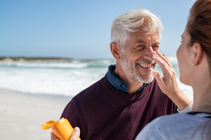 applying sunscreen cream on a middle aged man's face