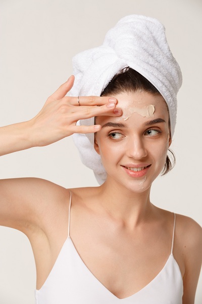 Beauty treatment - woman applying moisturing cream