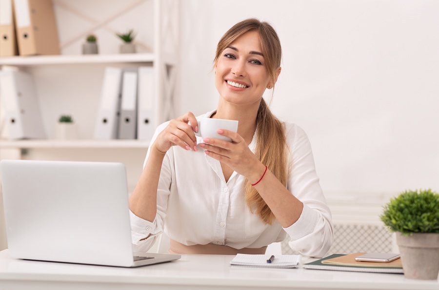 business woman holding coffee and smiling at her office