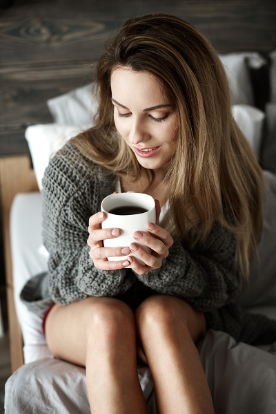Pretty woman with coffee mug on bed