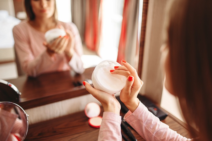 woman applying acne cream in front of the mirror